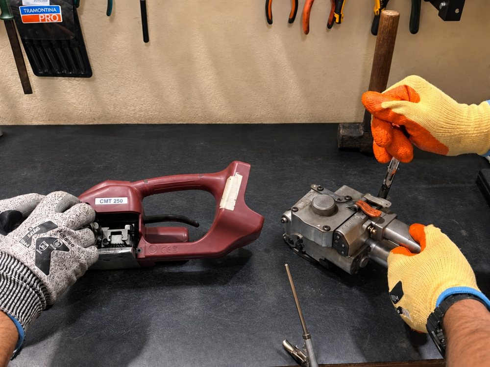 Detalhe do conserto: técnicos com luvas de proteção manuseando aparelhos de arqueação